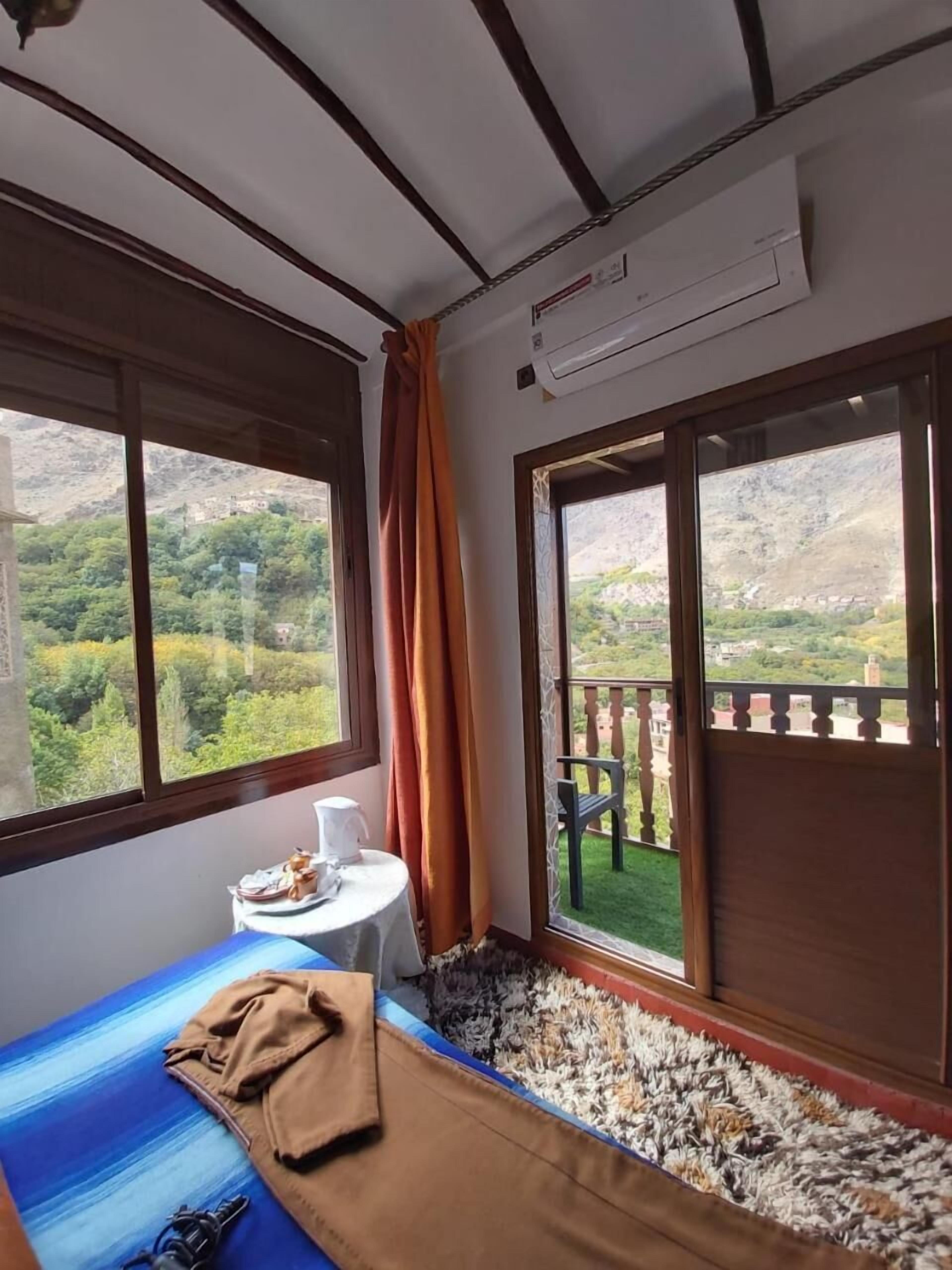 Una habitación con una cama, una mesa con una taza y vistas a un paisaje montañoso.