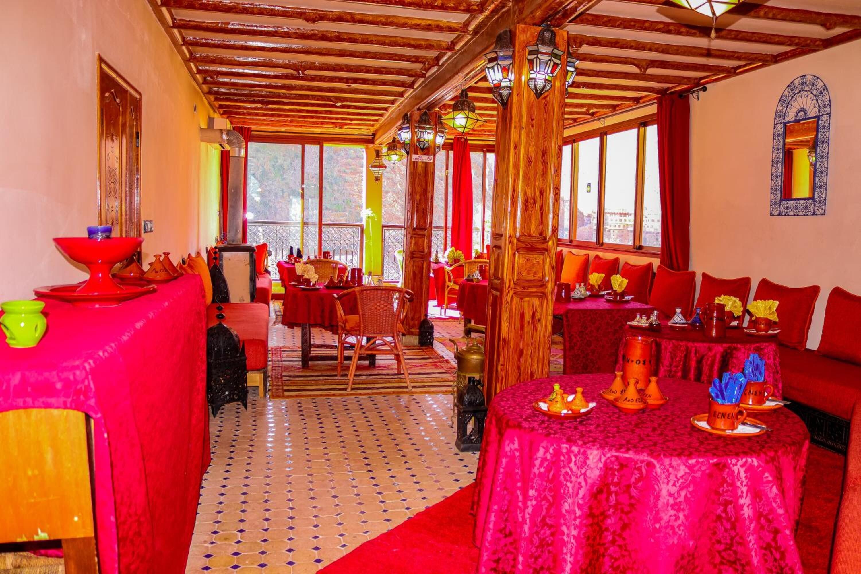 A restaurant with red and orange decor, wooden beams, and a tiled floor.