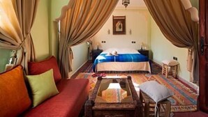 Quarto tradicional com uma cama, um sofá e uma mesinha.
