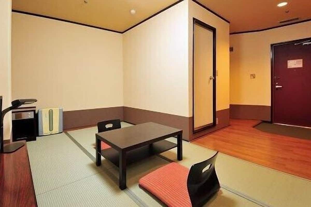 A small room with a wooden table, two chairs, a television, and a door.