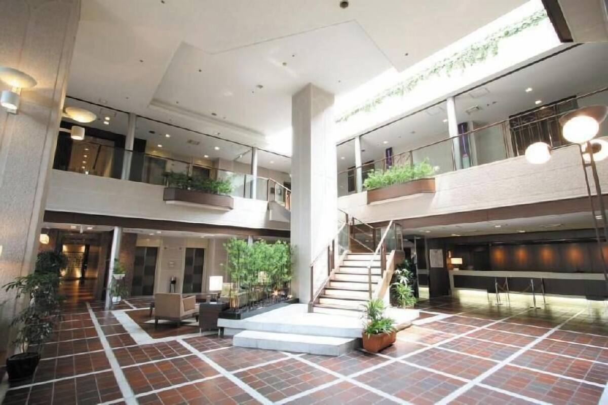 A spacious indoor area with a central staircase, multiple levels, and potted plants.