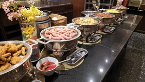 A buffet with various food items and a vase of flowers. - CYPRESS HOTEL Nagoya-eki Mae (Nagoya)