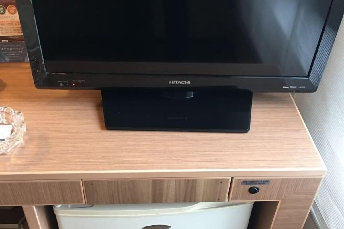 Een HITACHI televisie op een houten bureau met een witte lade eronder.