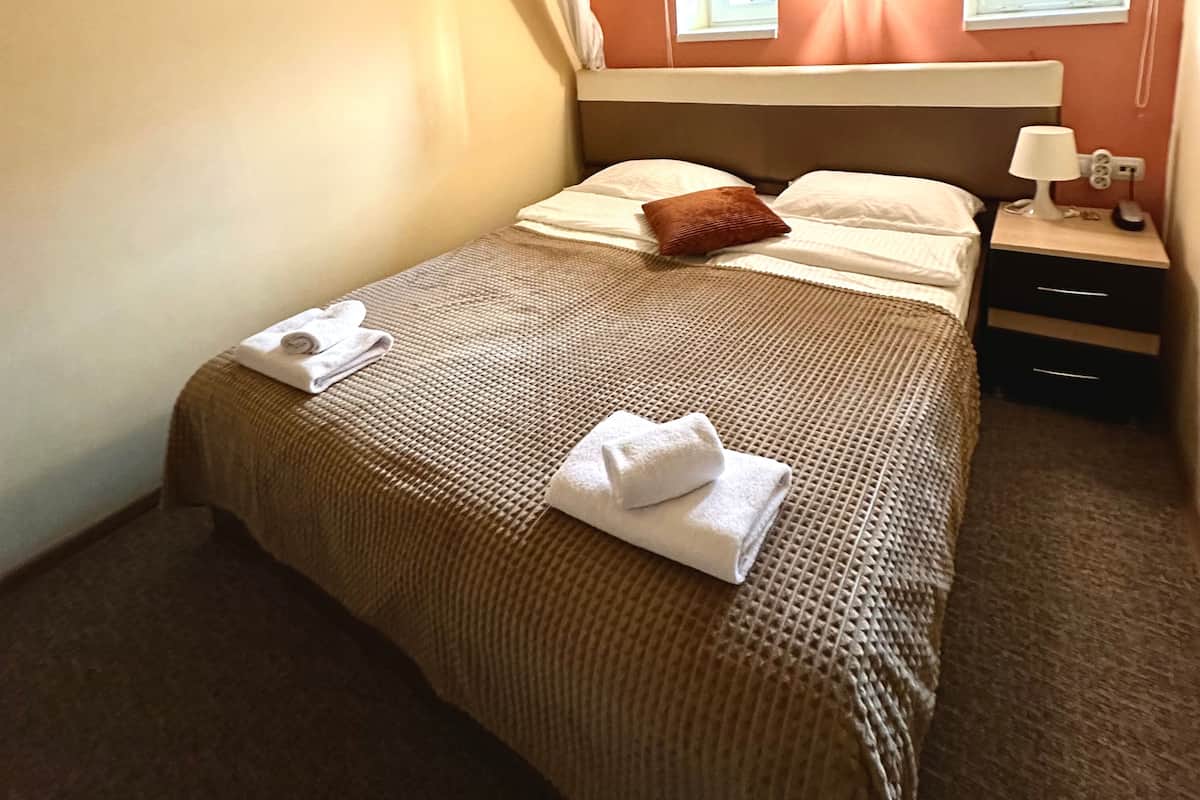 A hotel room with a bed, a nightstand, a lamp, and a painting on the wall.