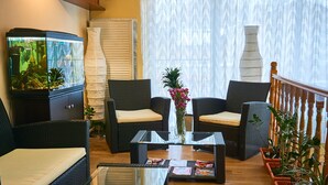 A living room with wicker furniture, a glass coffee table, and a fish tank. - Leotel Hotel (Lviv)
