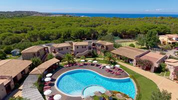 Relax by the central pool surrounded by sun loungers and umbrellas, offering a serene sea view.