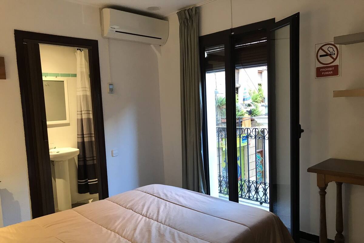 A hotel room with a bed, a bathroom, and a balcony with a view.