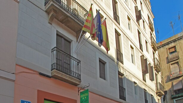 Un edificio con un letrero que dice Hostal Radio, balcones con barandillas de metal y banderas.
