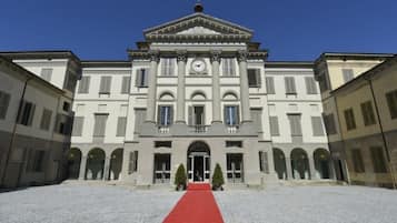 A large, symmetrical building with a central entrance, flanked by two wings, and a red carpet leading to the entrance.