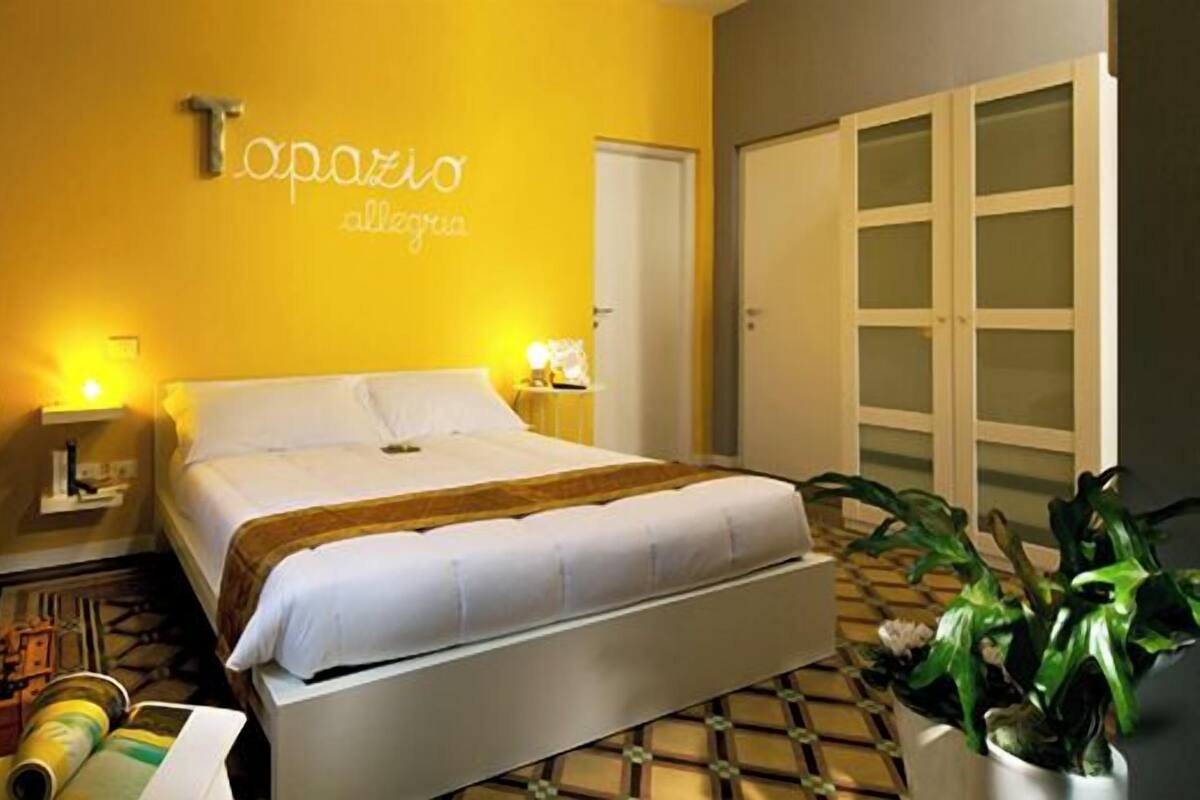 A hotel room with a bed, bedside tables, a small desk, and a chair.