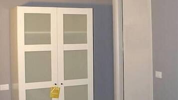 Une pièce avec une armoire blanche, un banc et une porte.