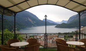 A terrace with wicker chairs and a table, overlooking a lake and mountains. - Hotel Florida (Molveno)