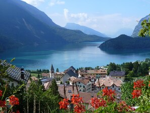 A lakeside village with traditional houses, a church, and mountains in the background. - Hotel Florida (Molveno)