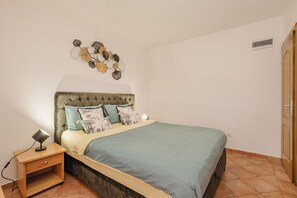 A bedroom with a bed, bedside table, lamp, and wall art. - Apartments Djurasevic (Blizikuce)