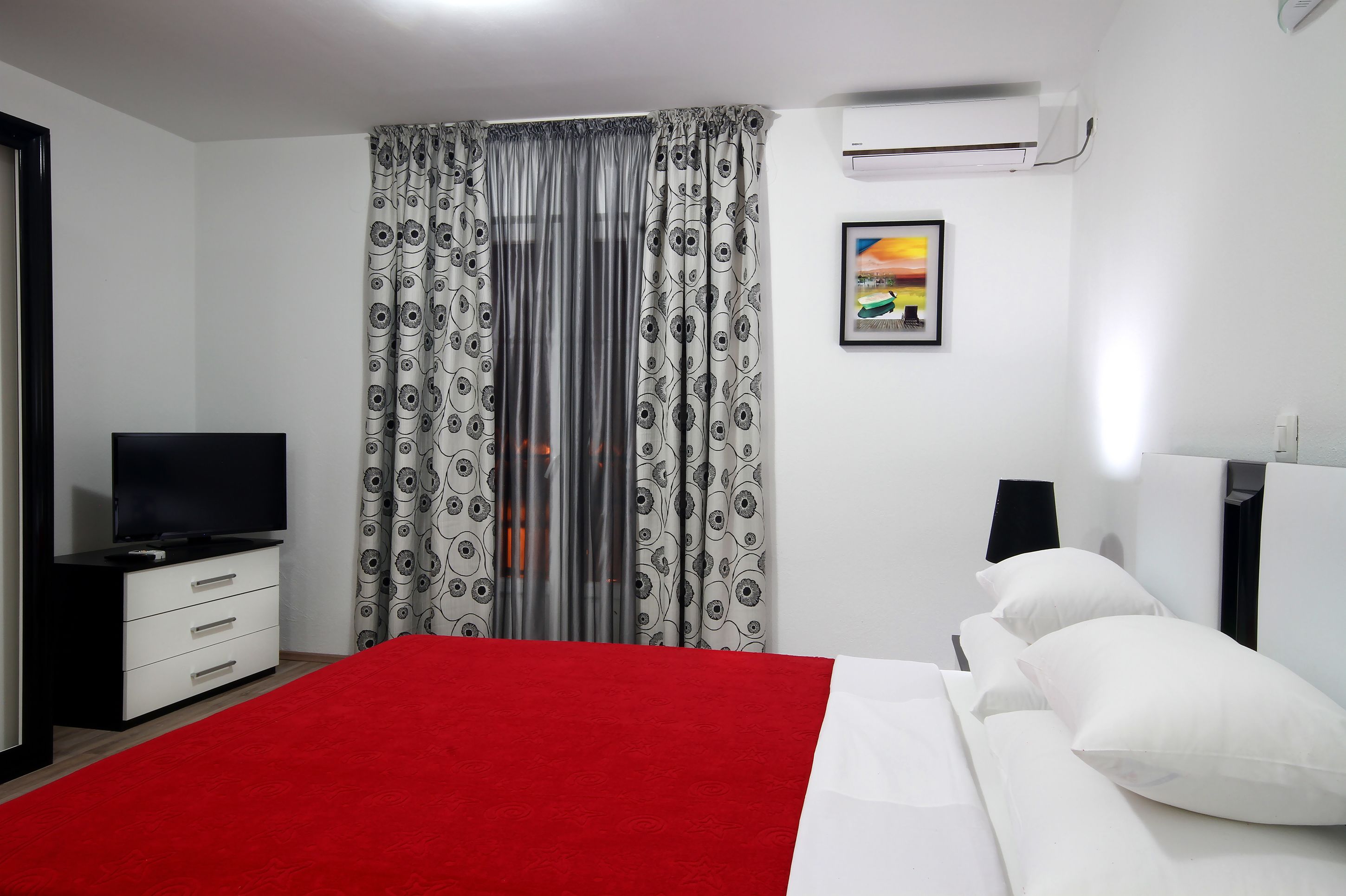 Ein Schlafzimmer mit einem Bett, einem Fernseher, einem Nachttisch und einer Wand-Klimaanlage.