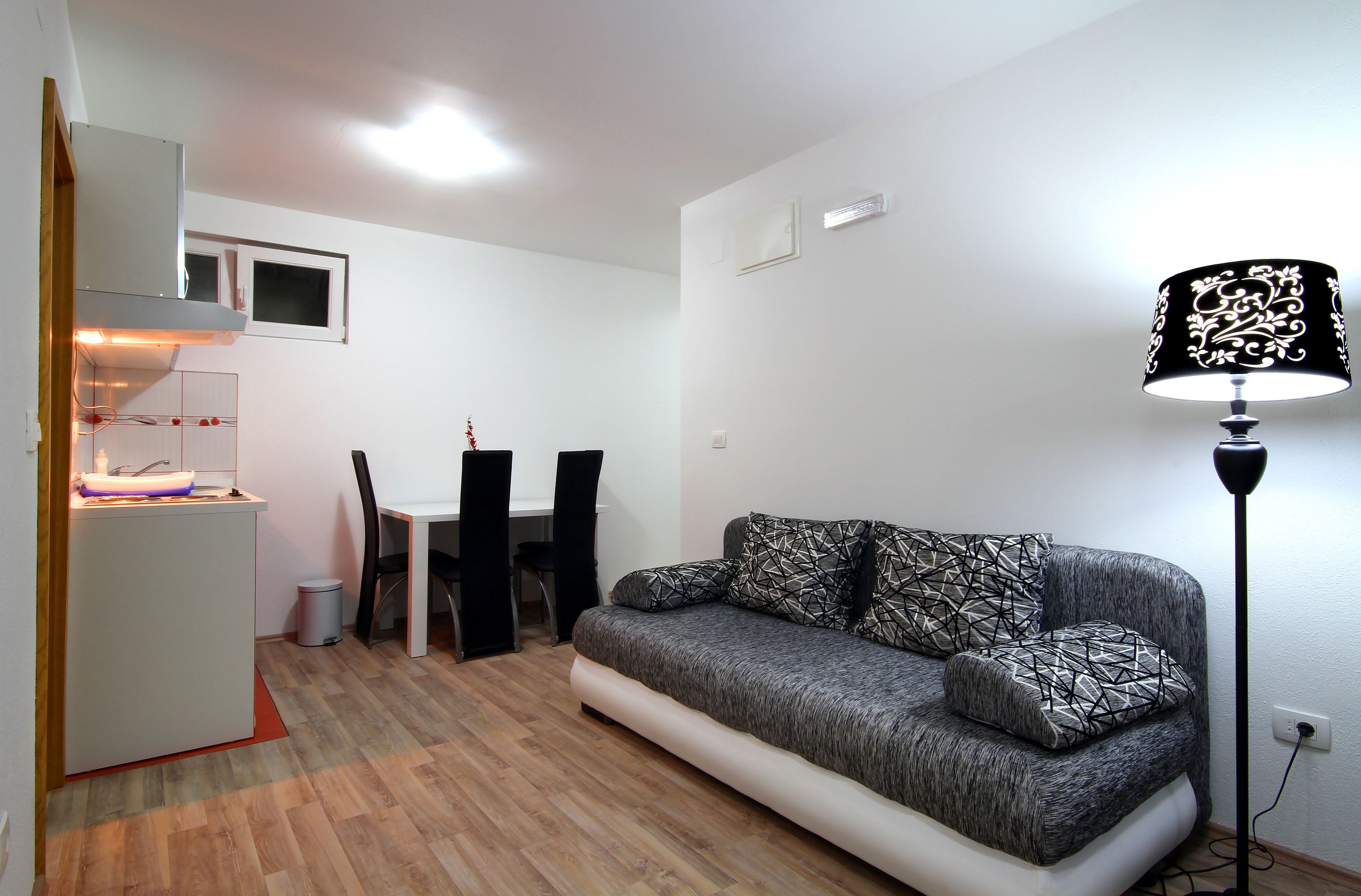 A compact living space with a kitchenette, a dining area, and a sofa with patterned cushions.