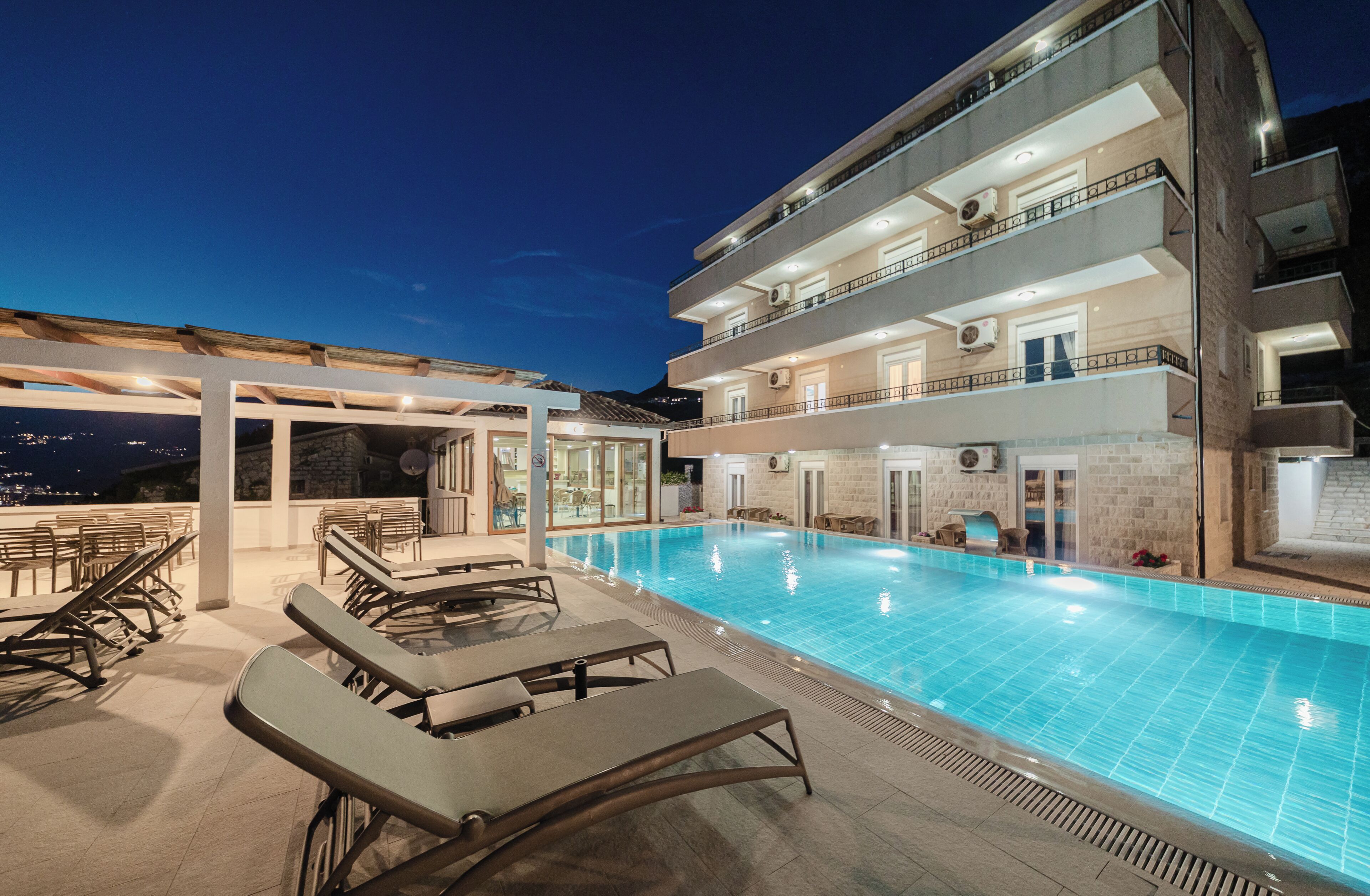 Una piscina al aire libre, sombrillas, sillones reclinables de piscina