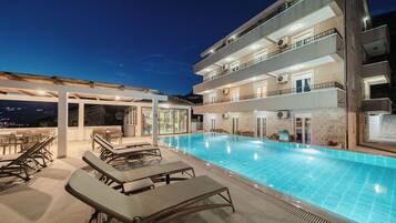 Una piscina al aire libre, sombrillas, sillones reclinables de piscina