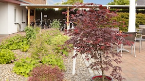 A garden with various plants and a bicycle. - Ferienhotel Bernstein (Trassenheide)