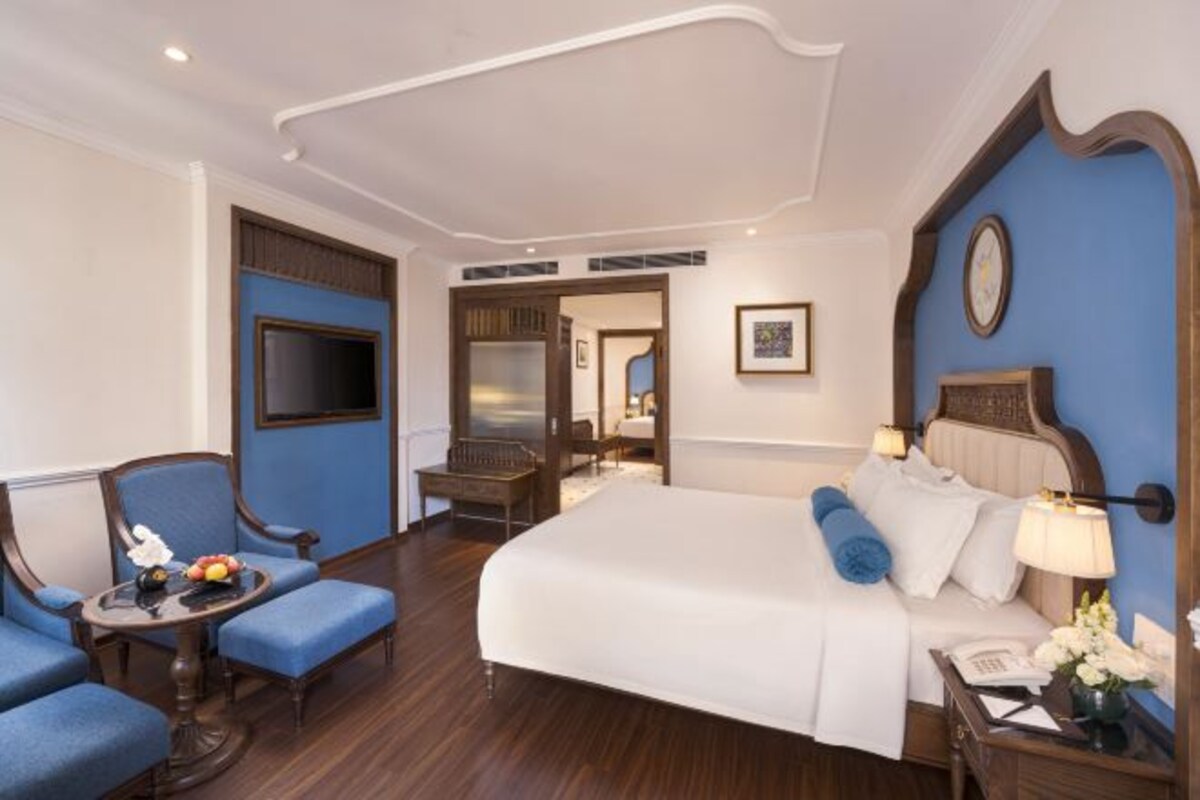 Een hotelkamer met een groot bed, een bureau met telefoon, een stoel en een televisie.