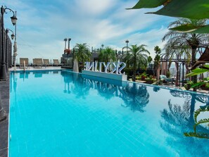 A swimming pool with lounge chairs and a view of the city skyline. - Tirant Hotel (Hanoi)