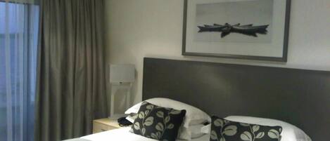 Une chambre d’hôtel avec un lit, une table de chevet, une lampe et un tableau encadré au mur.