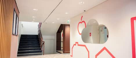 A modern interior with a staircase, a wall with geometric patterns, and a ceiling with recessed lighting.
