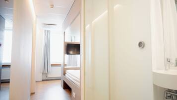 A hotel room with a bed, a TV, a bathroom with a sink, and a window with curtains.