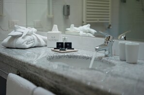 A bathroom with a granite countertop, a towel, a mirror, and toiletries.