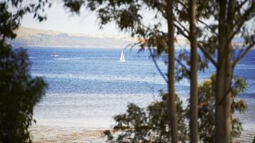 A view of a body of water with a sailboat and a coastline in the distance.