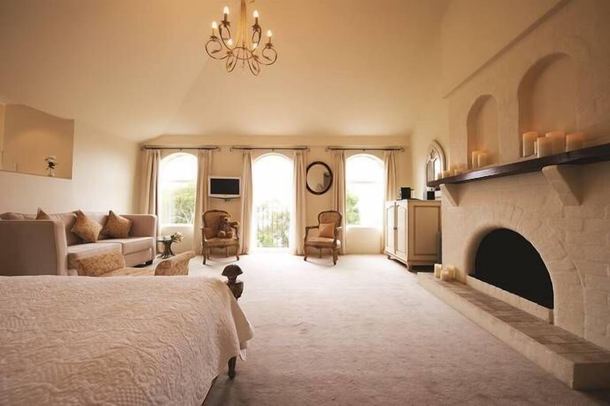Un dormitorio con cama, chimenea, televisión y un ventanal grande.