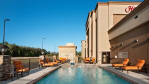 A swimming pool with lounge chairs, a hotel building with a 'H' logo, and a clear blue sky. - Hampton Inn Magnolia (Magnolia)