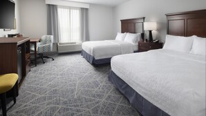 A hotel room with two beds, a desk with a chair, a TV, and a window with curtains. - Hampton Inn Magnolia (Magnolia)