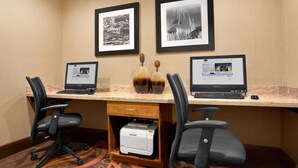 A conference room with two desks, each with a laptop, two framed black and white photographs on the wall, and a printer under one desk. - Hampton Inn Magnolia (Magnolia)