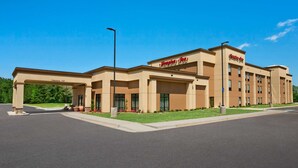 A Hampton Inn hotel with a clear entrance, a parking lot, and a well-maintained lawn.