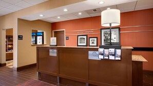 A reception desk with a sign reading "welcome to magnolia," framed pictures, and a lamp.
