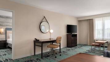Une chambre d’hôtel équipée d’un lit, d’un bureau, d’une chaise, d’une télévision et d’une grande fenêtre.