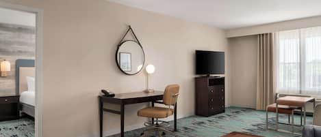 A hotel room with a bed, desk, chair, TV, and large window.