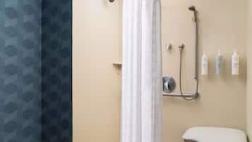 Ein Badezimmer mit Dusche, Toilette und drei Shampooflaschen an der Wand.