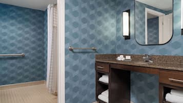 A bathroom with a shower, a vanity with a mirror, and a towel rack.