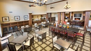 A spacious dining area with multiple tables and chairs, a bar area with a flat-screen TV, and a fireplace. - Homewood Suites by Hilton Newport Middletown, RI (Middletown)