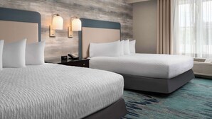 A hotel room with two beds, a wooden textured wall, two wall-mounted lamps, and a large window with sheer curtains. - Homewood Suites by Hilton Newport Middletown, RI (Middletown)