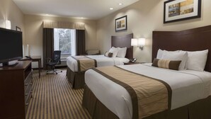 A hotel room with two beds, a desk with a television, a chair, and a window with curtains. - Baymont by Wyndham Victoria (Victoria)