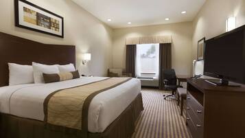 A hotel room with a large bed, a desk with a chair, a television, and a window with curtains.