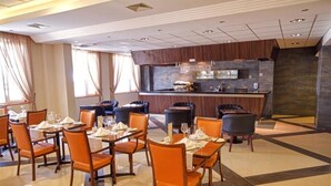 Un comedor de hotel con mesas y sillas, un bar y una cocina al fondo.