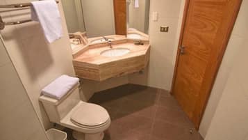 A bathroom with a toilet, a sink, and a mirror.