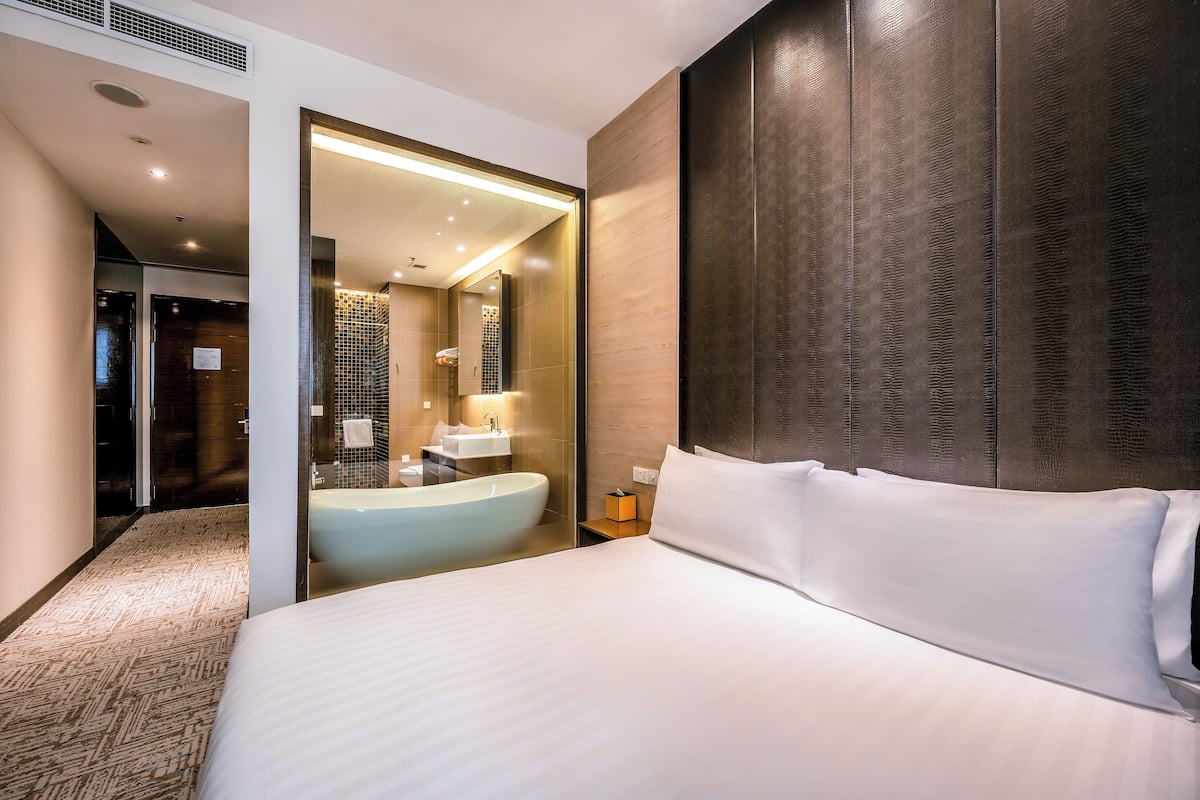 Ein Hotelzimmer mit einem großen Bett, einer Badewanne und einer separaten Duschkabine.