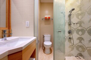A bathroom with a white sink, a toilet, and a shower area with mosaic tiles.