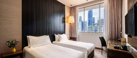 A hotel room with two beds, a desk, a chair, a TV, and a large window with a city view.