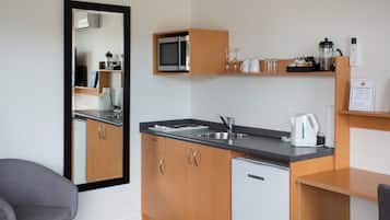 A compact kitchen with wooden cabinets, a microwave, a sink, and a coffee maker.